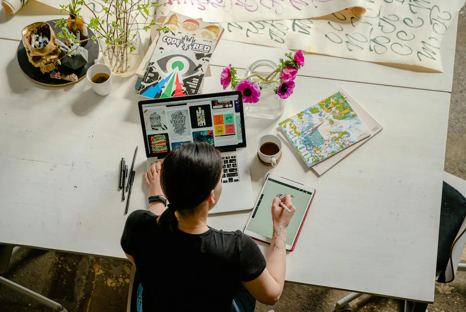 Photo of Woman Writing on Tablet Computer While Using Laptop