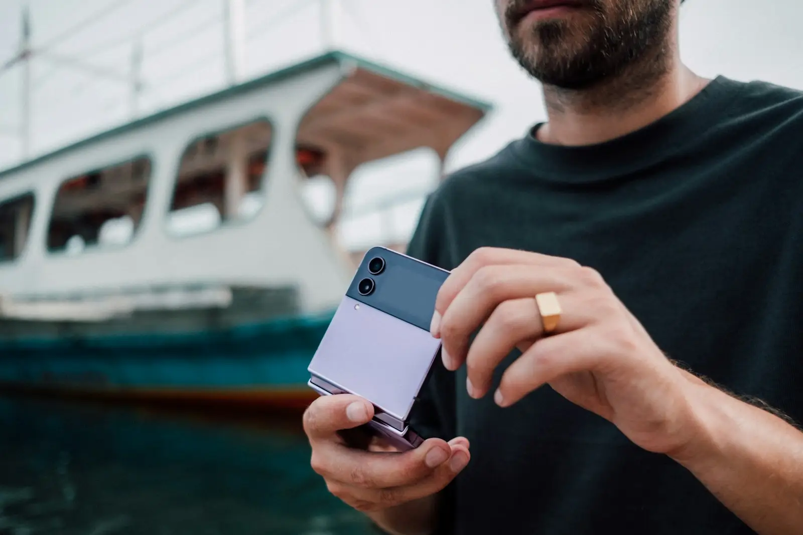 a man holding a cell phone in front of a boat