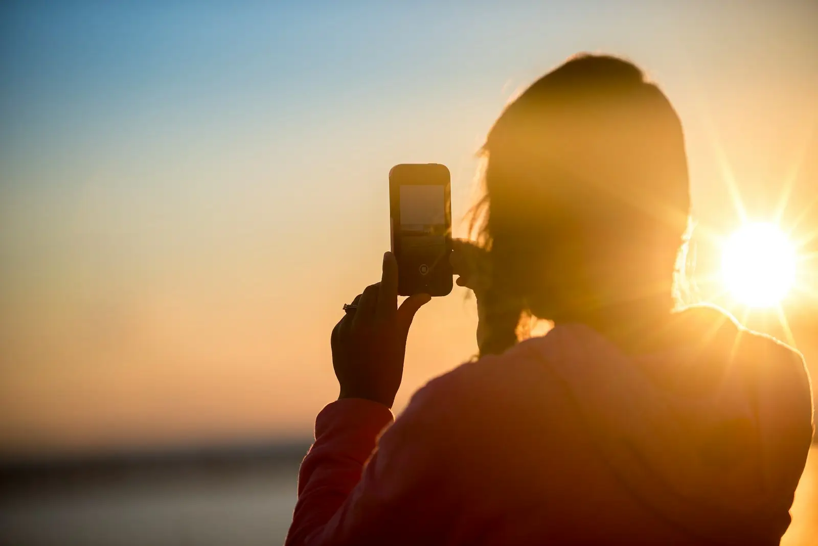 woman taking photo of sunset