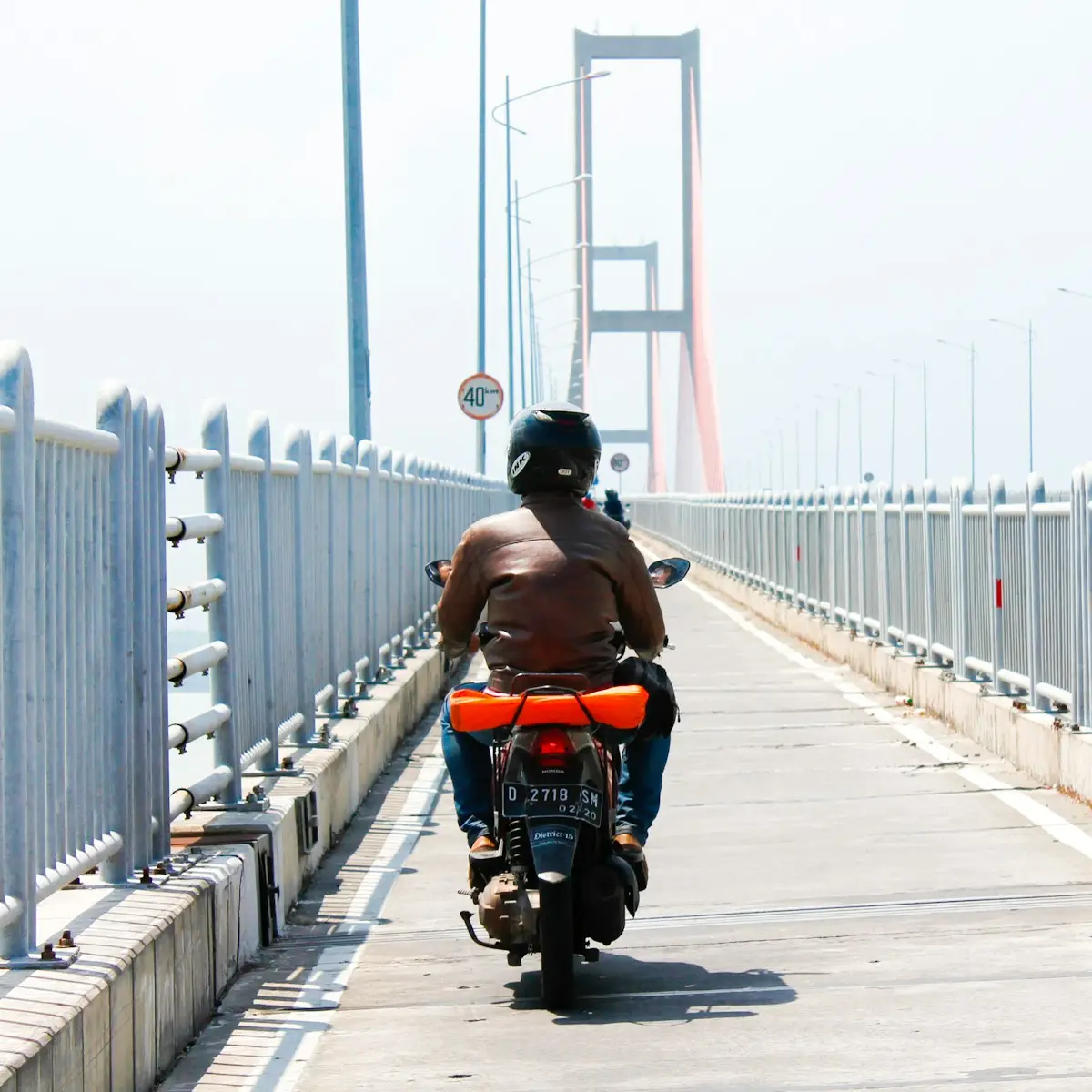 a man riding a motorcycle across a bridge