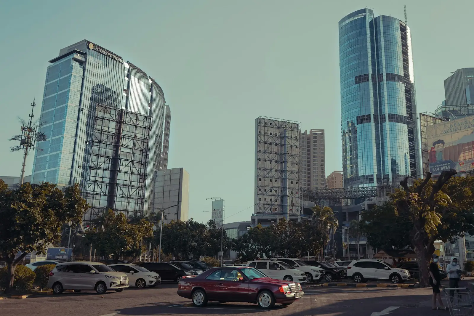 cars parked on parking lot near high rise buildings during daytime